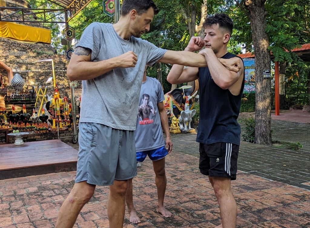 Two men practising Muay Thai at a shrine in Thailand
