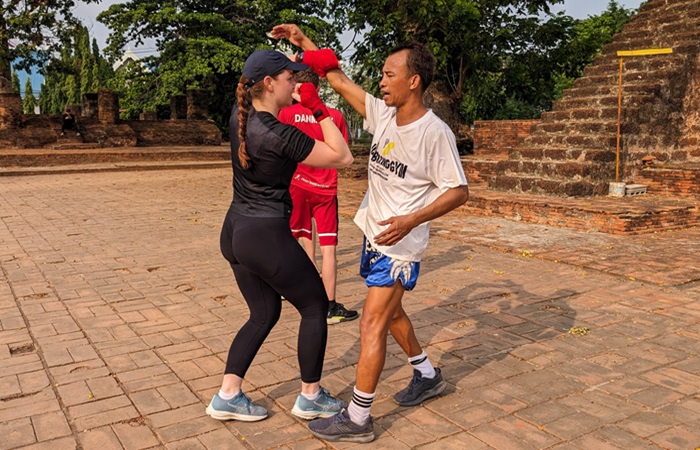 A woman is practising Muay Thai with a teacher